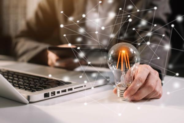 innovation, lightbulb on a desk next to a laptop